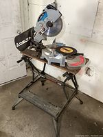 Delta compound miter saw mounted on Black & Decker Workmate with spare DeWalt blade on work surface.
