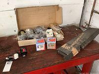 Overview photo showing a box containing various motorcycle parts including horns, electrical components, and boxed spring set.