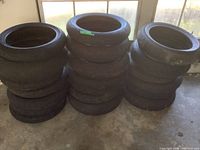 Three stacks of used motorcycle tires, about 7 tires per stack, showing sidewalls and tread from distance.
