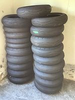 Stacked view of 20 used motorcycle tires showing tread and size variety