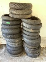 Stack of 25 used motorcycle tires showing varying tread depth and wear.