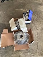 Pair of new 6 bolt drum brakes with shoes in original boxes placed on concrete floor.