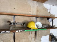 Photo of wooden shelf with vintage weigh scale, yellow hard hat, and two desk lamps