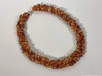 Full view of the amber nugget necklace laid flat in an oval shape, showing overall length and chunky bead texture.