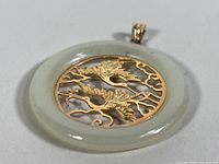 Front view of the jade eternity disc pendant with two detailed gold-tone cranes and cloud motifs at center.