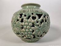 Front view of green celadon pot showing detailed grape and leaf reticulated design.