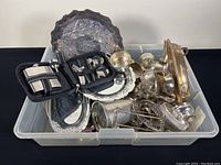 Full overview of assorted vintage silver plate and pewter servingware items arranged in a plastic bin.