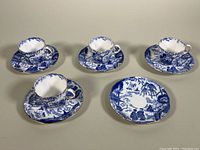 Four demitasse teacups and five saucers arranged side by side showing matching Blue Mikado pattern and condition.