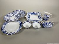 Full lot view showing creamer, sugar bowl, two plates, 10-inch bowl, two teacups, and Delphine cake plate all in Blue Mikado pattern by Royal Crown Derby.