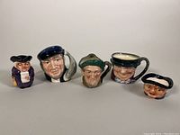 Five Royal Doulton porcelain Toby mugs and character ceramics shown from left to right, highlighting various expressions and hats.