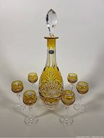 Full lot of decanter with stopper and six goblets arranged in front on flat surface against white background