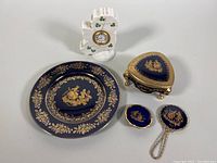 Overview of lot showing cobalt blue porcelain plate, trinket dishes, handheld mirror and shamrock mantel clock