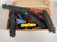 Overhead view of box containing various HO scale model train cars including cranes, gondolas, and flatcars