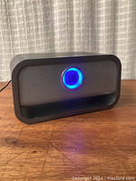 Front view of the Brookstone wireless speaker powered on with blue LED light visible.