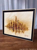 Framed abstract cityscape painting showing textured oil brush strokes and warm color palette