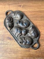 Top view showing the outer form of the pan with five sleeping cat and one sleeping puppy figures molded into the cast iron surface, basket shape with two handles.