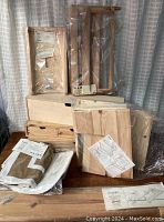 Photo showing various packaged wooden storage and shelf components along with textiles, some with tags and assembly instructions visible.