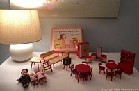 Overview of all three sets of furniture and three dolls arranged with a lamp in background