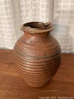 Front view of the pottery vase showing ridged body and brown iron oxide glaze.