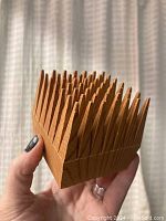 Front angled view showing the spiked wooden design of the pencil holder, held in hand for scale.