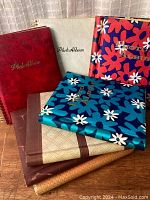 Photo of seven vintage photo albums arranged in two stacks showing various cover designs including floral patterns and plain covers.