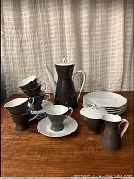 Full set including coffee pot, cups, saucers, cream, sugar bowl, and side plates arranged on table.