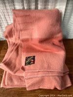 Full view of folded pink wool blanket showing texture and warmth.