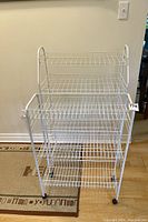 Full view of two white wire racks, one taller 6-tier stationary rack and one shorter 3-tier rack on wheels.
