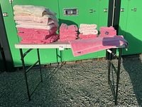 Overall view of the lot showing all towels laid and stacked on a table with green background.