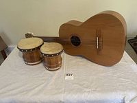 Side view showing both bongo drums and acoustic guitar on a white cloth.