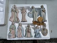Overview of 9 ceramic nativity figurines arranged in polystyrene packaging.