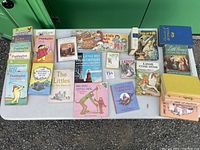 Photo of large lot of vintage children's books displayed on table including multiple Paddington books, Lassie books, The Wonderful Wizard of Oz, Little Women, and other classic children's stories.