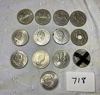 Lot of 13 coins spread on fabric showing obverse and reverse sides including Churchill Crowns and Elizabeth II Silver Jubilee coins.