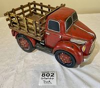 Red vintage collectible truck figurine with wooden rear bed, shown from side angle.