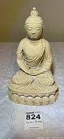 Front view showing the Buddha statue in seated meditation pose with serene expression and detailed robe drapery.