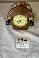 Front view showing clock face, Peetz logo, and black winding knobs on wooden reel sides.