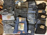 Group photo showing various folded jeans in denim and black with brand tags visible including Wrangler, West49, and Freeworld.