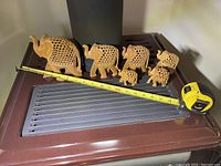Six intricately hand-carved jali wooden elephant figurines arranged in a row with measuring tape showing length.