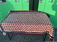 Full view of rug draped over table showing overall pattern and condition