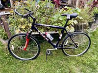 Full profile view of the Trek 6000 mountain bike in grass with surrounding plants, highlighting frame and components.