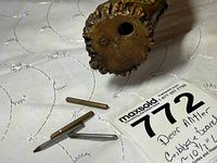 Close-up of three metal cribbage pegs beside the base of the deer antler cribbage board showing rugged natural texture.