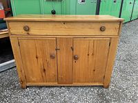 Front view of handcrafted wooden sideboard with three cabinet doors and a single drawer at the top, showing natural wood finish and round wooden knobs.