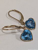 Pair of yellow gold earrings with heart-shaped faceted blue topaz stones on lever back clasps.