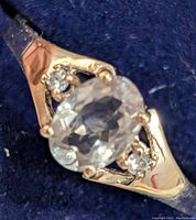 Close-up image of the 10K gold ring featuring an oval Zultanite center stone with two small diamonds on each side set in triangular yellow gold sections.