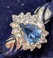Close-up top view showing pear-shaped blue sapphire and surrounding diamond halo.