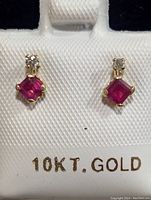Close-up photo of a pair of 10K gold stud earrings with square ruby and round diamond above each ruby, displayed on white earring card stamped 10KT GOLD.