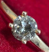 Close-up top of the ring showing round diamond and six-prong setting on yellow gold band.