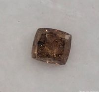 Close-up of a brown cushion cut diamond showing facets and natural inclusions.