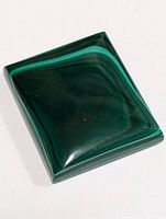 Polished rectangular malachite gemstone showing typical green banded pattern on domed surface.