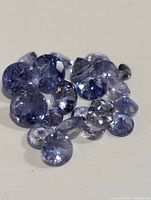 Close-up of various loose tanzanite gemstones in shades of blue-violet, highlighting size and clarity differences.